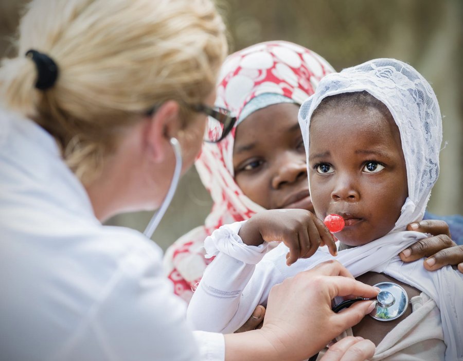 A clinician using a stethoscope to examine a young child